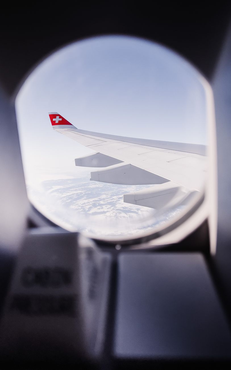 airplane wing view with swiss flag from window
