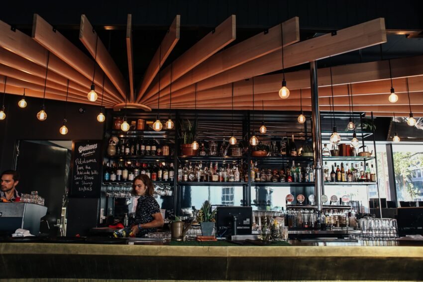 shelves beams and lights over men behind a bar